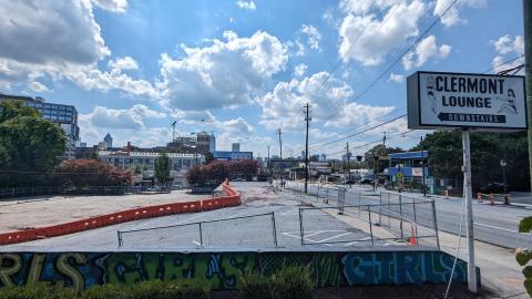 A photo of a large cleared parking lot with a Clermont Lounge sign next to it, under blue skies.