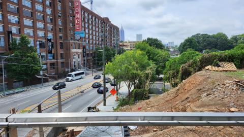 A photo showing a construction site where a ramp is being built near a wide path and busy street.