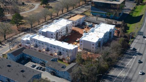 An image of a large building project with townhomes and apartments next to an interstate. 