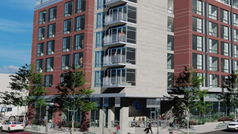 An image showing plans for a red brick and white-clad mid-rise hotel facing three different streets under blue skies.