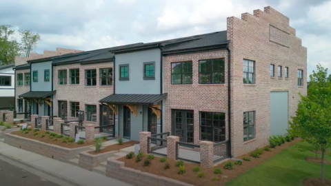 A new townhome development under blue skies near green trees south of downtown Atlanta, with white interiors.