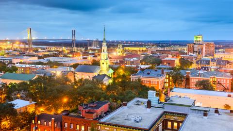 A photo of a historic river city with many old buildings under a blue sky near a large bridge.