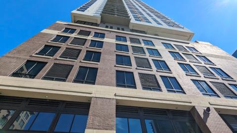 An image of a tall brick, glass, and white stucco building on a wide downtown Atlanta street with modern interiors under blue skies.