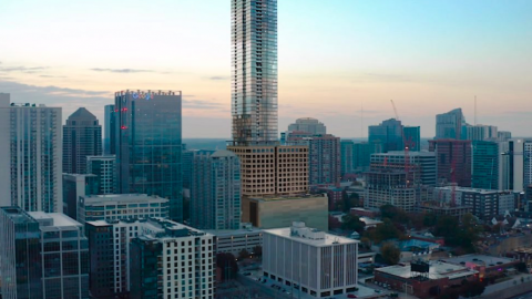 An image of a tall glassy skyscraper near many glassy smaller buidings in Atlanta under gray skies. 