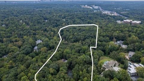 An image showing a large house from the 1950s and a huge plot of land with many trees and a babbling creek. 