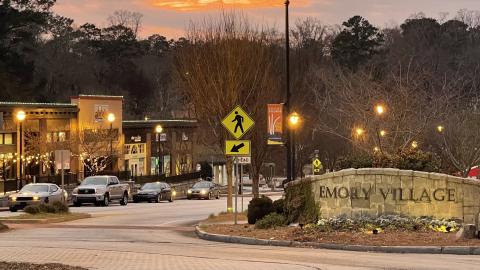 A row of historic storefronts near a traffic roundabout under streetlights near Emory University. 