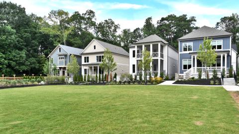 An image of large houses with balconies under blue skies arranged around woods and open greenspaces where a farm will be placed.