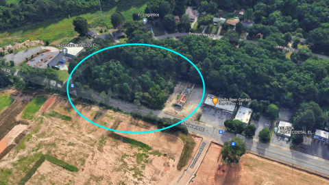 An image showing a large development site next to a wide street and many trees and homes a low commercial building in Atlanta.