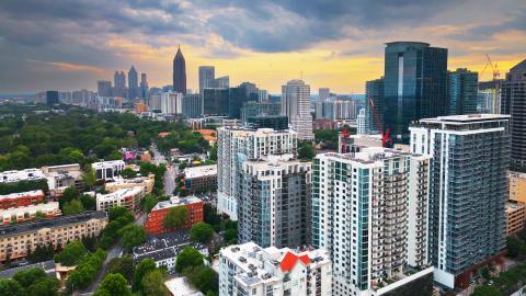 A drone photo showing Atlanta's skyline under cloudy skies with many trees to the bottom and left.