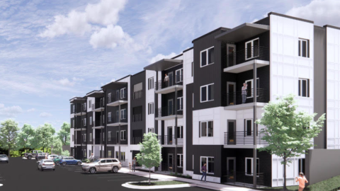 A gray and white apartment box under blue skies near a wide parking lot outside Atlanta.