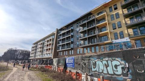 A photo of a large apartment complex under construction with a wide trail beside it to the left.