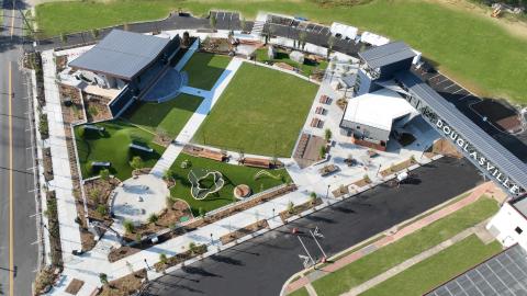 An image showing a new lawn and playground and amphitheater near historic building and wide streets in suburban Atlanta.