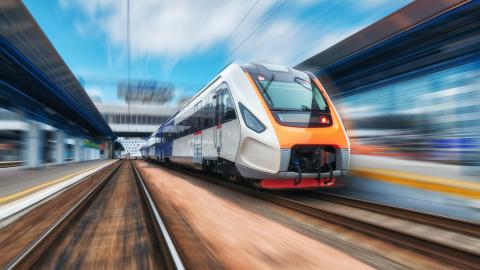 A blurred photo of a high-speed train moving fast between two buildings in Europe. 