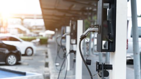 A photo of an EV charging station with black and white cars lined up. 