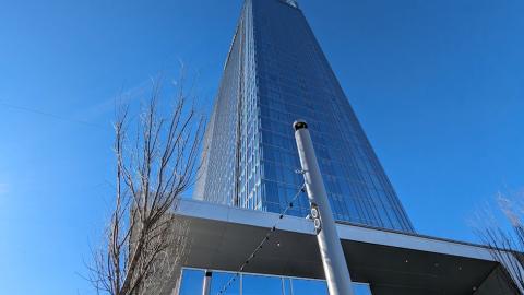 A photo of a large hotel with a glassy rectangular exterior and a vast modern interior with room with white walls and city views.