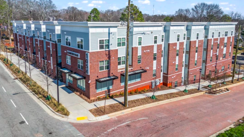 A photo of a large affordable housing apartment complex next a brick and asphalt street in Atlanta, with white modern interiors. 