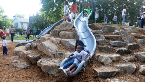 A photo of a public park in Atlanta with many children playing on slides and rocks. 