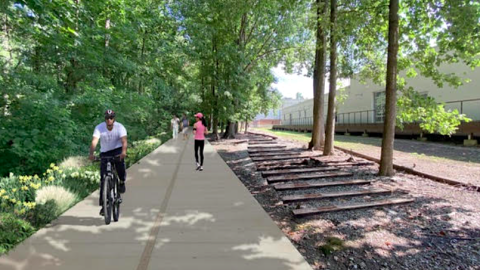 An image of a rail trail section west of Atlanta next to industrial facilities and a creek.