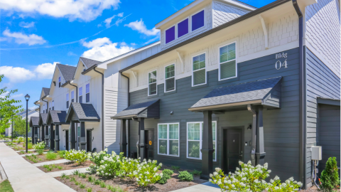 A photo of a large suburban apartment complex with many white and blue and gray buildings under blue skies outside Atlanta.