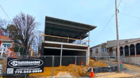 An image of a small building rising on an empty lot in Atlanta next to two businesses beside a wide street. 