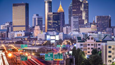 A photo of Atlanta Georgia's skyline under blue skies near a wide highway. 