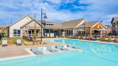 An image showing a large new apartment complex with a pool and white modern interiors with a large gaming room. 