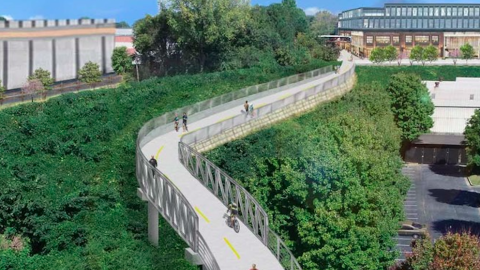 An image showing a long new trail built next to many woods and old and new buildings with a large bridge in the middle. 