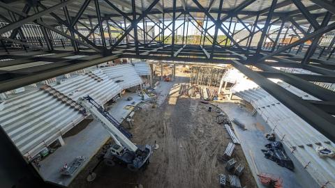 A photo of construction on a large new arena in downtown Athens with a dirt floor and many trees around in the distance.