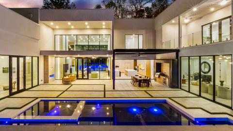 a photo of a large white modern house with a pool and huge white interiors spaces surrounded by trees in Atlanta. 