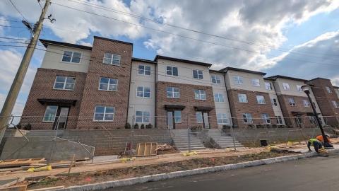 An image showing brick and stucco new apartments under blue skies with an asphalt street in front and modern-style interiors in Atlanta.