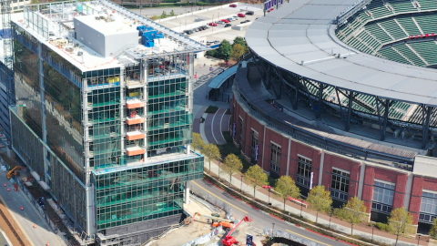 An aerial photo of a new office complex that's taken shape behind the Atlanta Braves stadium with glass and concrete near the stadium's brick walls. 