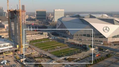 An aerial over downtown Atlanta showing a long park space next to a large stadium.