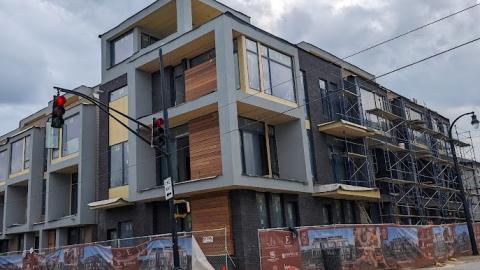 A photo of a new modern townhome complex that's taken shape on a corned in Atlanta under gray cloudy skies. 