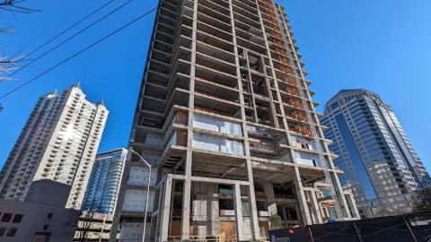 A photo of a very tall and stripped down skyrise under blue skies in Midtown Atlanta.