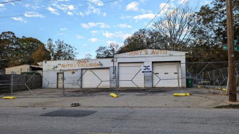 An old car auto garage shown under blue skies in front of a wide street in Atlanta.