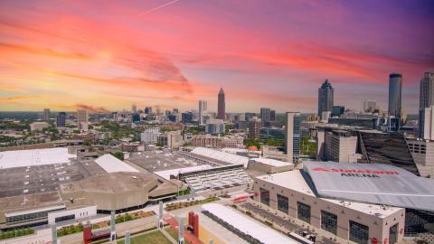 A massive convention and visitors center shown under pink and purple skies in Atlanta. 