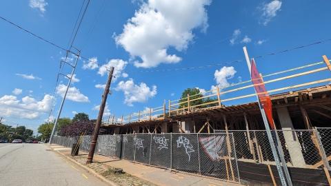 A photo of a large construction site with new concrete construction under blue skies next to a wide street in Atlanta.