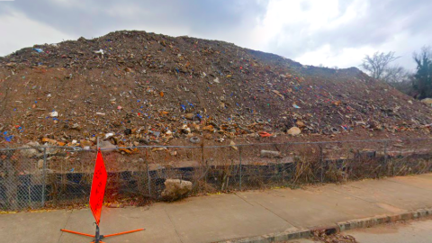 A huge brown mound of trash shown under gray skies near a city street in Atlanta.