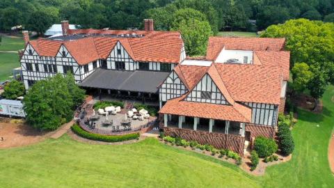 A photo over a golf course with lakes and a large Tudor-style clubhouse near many trees on Atlanta's eastside.