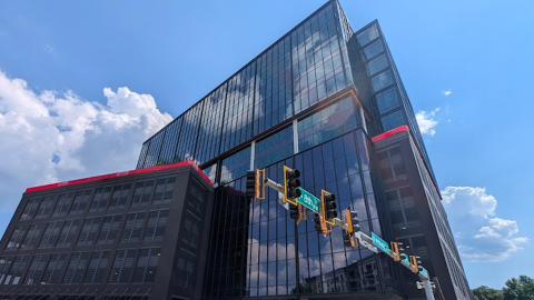 A photo of a large glassy black office building under blue skies in Atlanta, near wide streets.