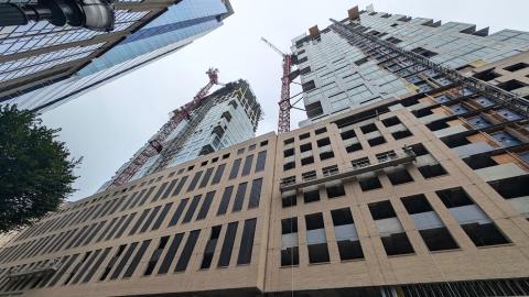 A photo of a two-tower large new development under gray skies in Atlanta near a wide street with two cranes above. 