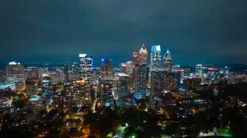 A photo at night over Piedmont Park in Atlanta overlooking a large city and many highways with glowing clouds above.