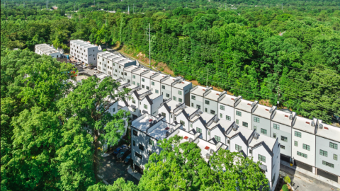 A photo showing rows of white tall new townhomes set among many trees near new streets in Atlanta.