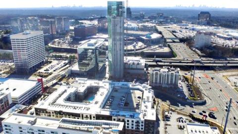 A photo of a large tower and a new district with a wide street at right. 