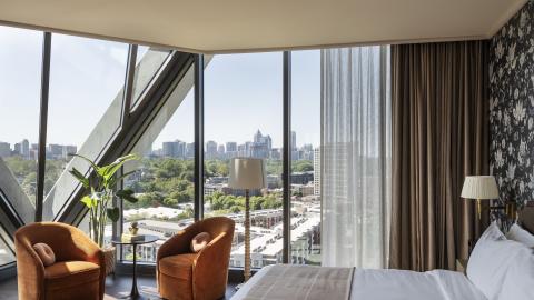 A photo of a large new hotel in Atlanta near treetops and a large walking path with modern-rustic rooms in a new tower with a diamond-patterned exterior.