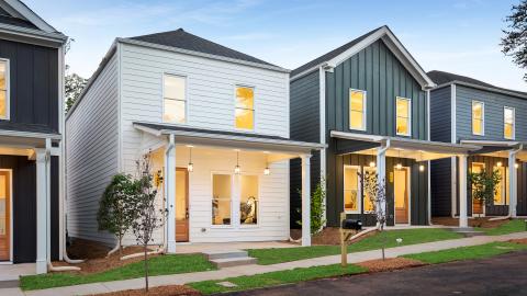 A photo of a row of new modern-style houses on an asphalt street on the southside of Atlanta under blue skies. 