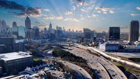 A huge glorious city skyline with a giant highway in the middle and a sunset in the distance.