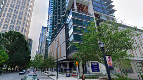 A photo of a row of retail storefronts along a busy street in Midtown Atlanta under gray-blue skies and a tall blue glassy building.