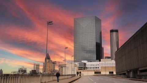 A photo of a sunrise over downtown Atlanta next to a wide street and bridge. 