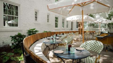 A photo of a large newly renovated hotel in Atlanta with white stucco walls and a large courtyard and European-inspired, cozy interiors, under blue skies.